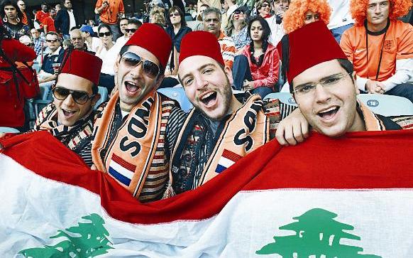 مشجعون لبنانيون يحملون علم بلادهم في مدرجات استاد «موزيس مابهيدا» قبيل انطلاق مباراة هولندا وسلوفاكيا (اف ب)