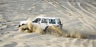 سيارة تشق طريقها وسط أمواج الرمال