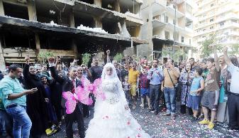 شاب وفتاة يحتفلان أول من أمس بزفافهما في موقع الانفجار في الرويس	 (أ ف ب)