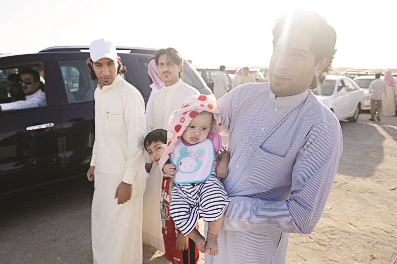 أحد رواد الحراج يحمل ابنه قبل التجول في السوق