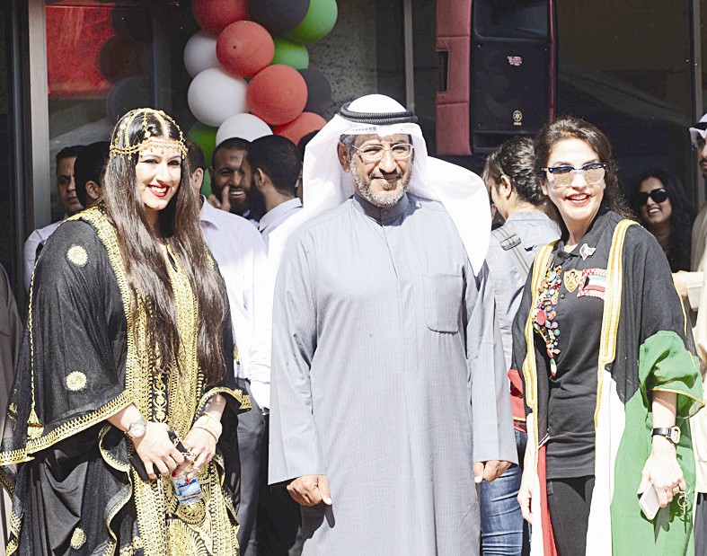 المطيري مع موظفتين بالزي الشعبي