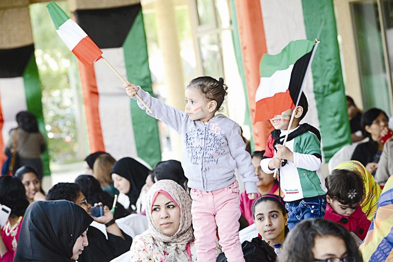أطفال يلوحون بالعلم الكويتي