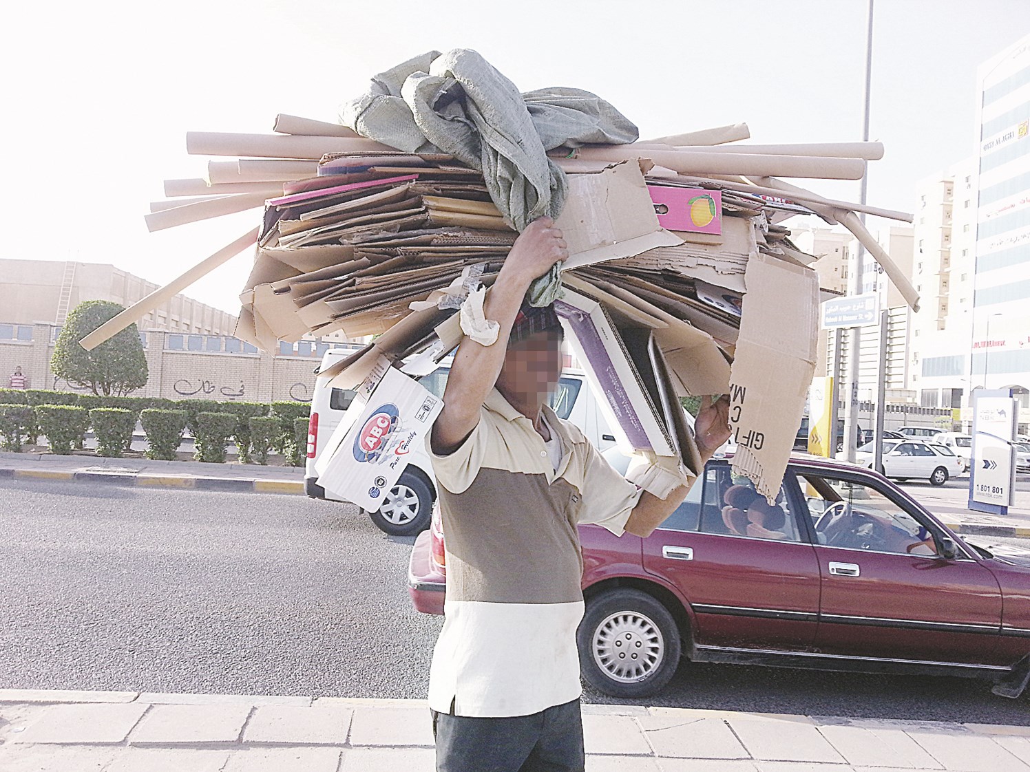 عامل يجمع الكراتين لبيعها مقابل 30 فلساً للكيلو