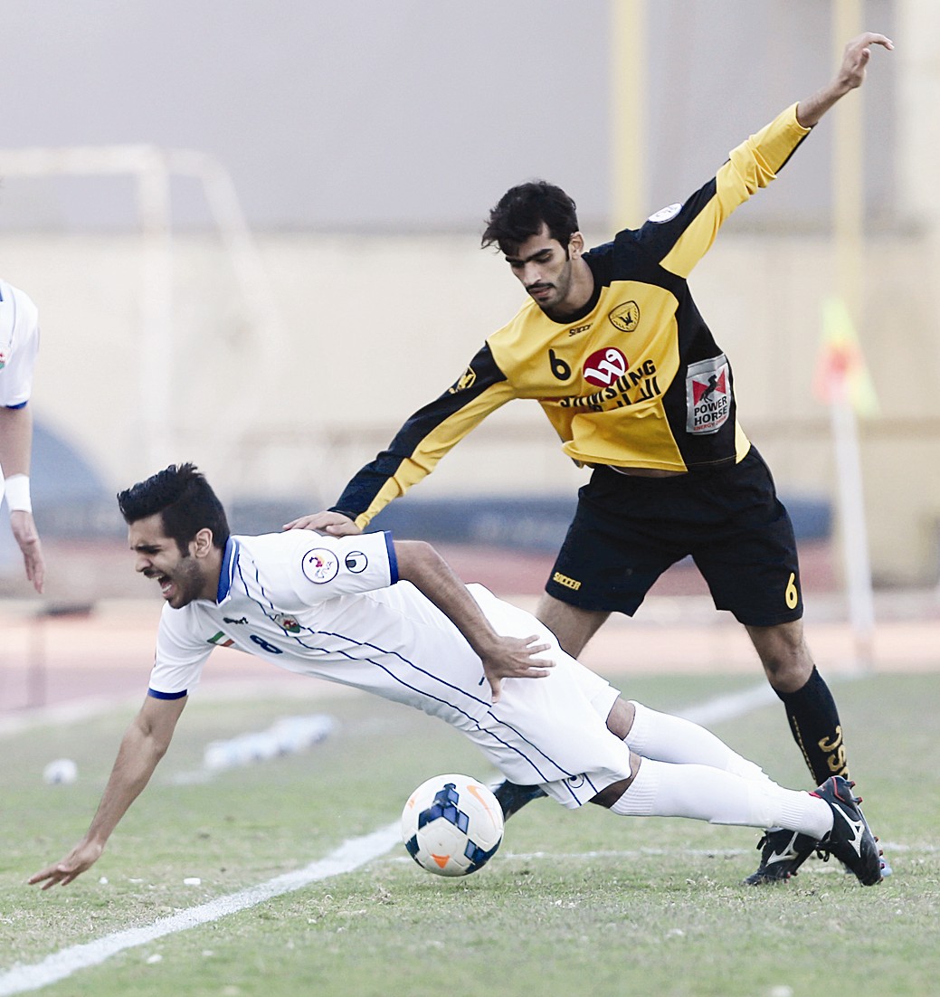 خالد القحطاني يحاول تمرير الكرة من أسفل فيصل زايد