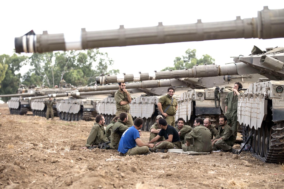 جنود إسرائيليون يجلسون قرب دبابات «ميركافا» على أطراف قطاع غزة أمس (ا ف ب)