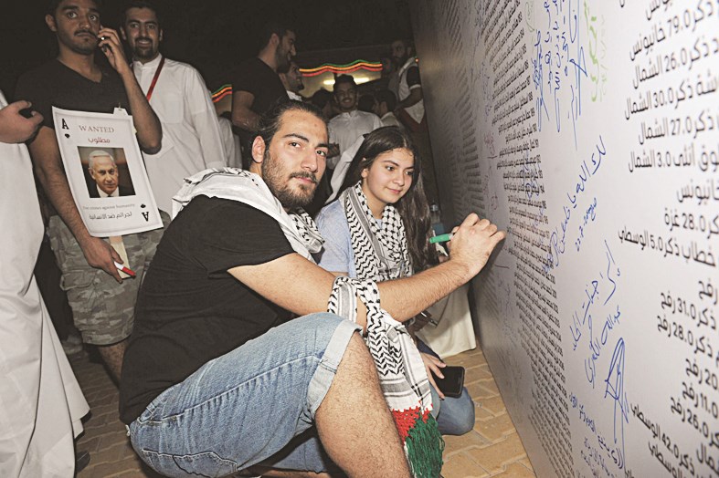 الحاضرون يدونون أسماءهم بجوار أسماء شهداء غزة (تصوير: نور هنداوي)