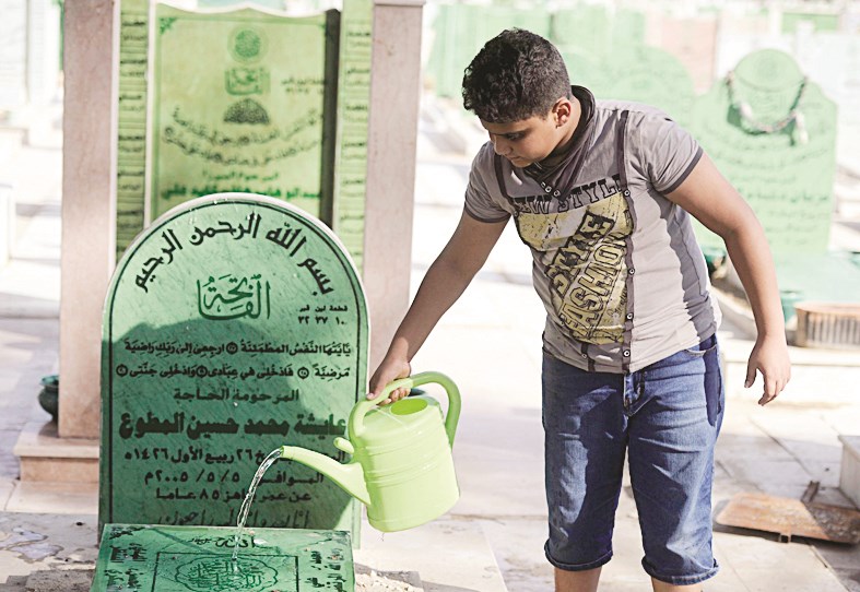 طفل يرش الماء على أحد القبور