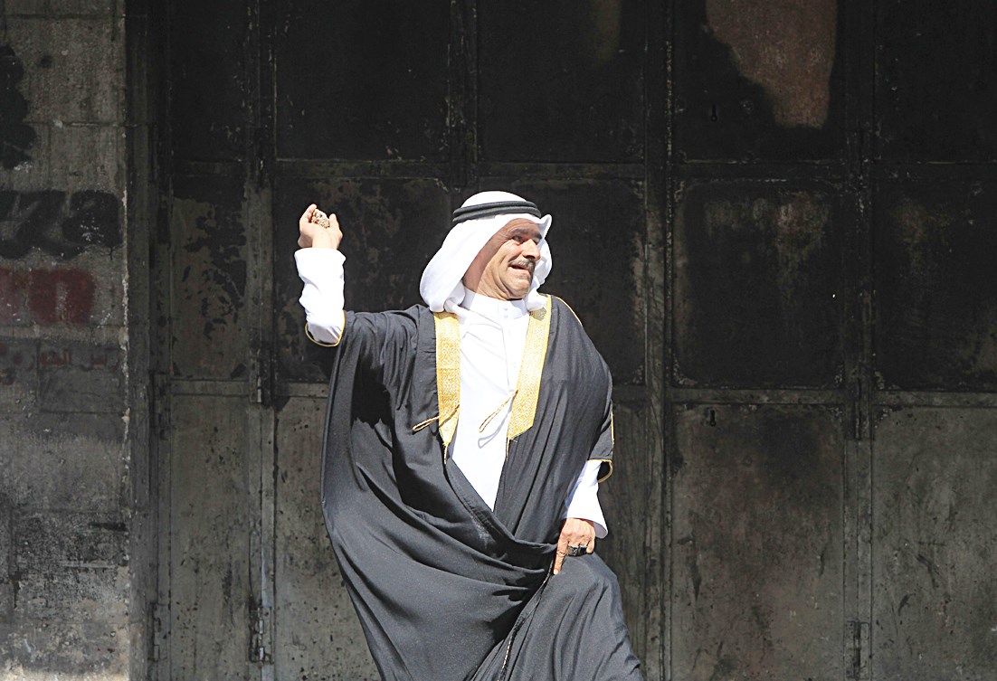 فلسطيني في الزي العربي يرشق جنودا إسرائيليين بالحجارة خلال مواجهات في الضفة أمس (أ ف ب)