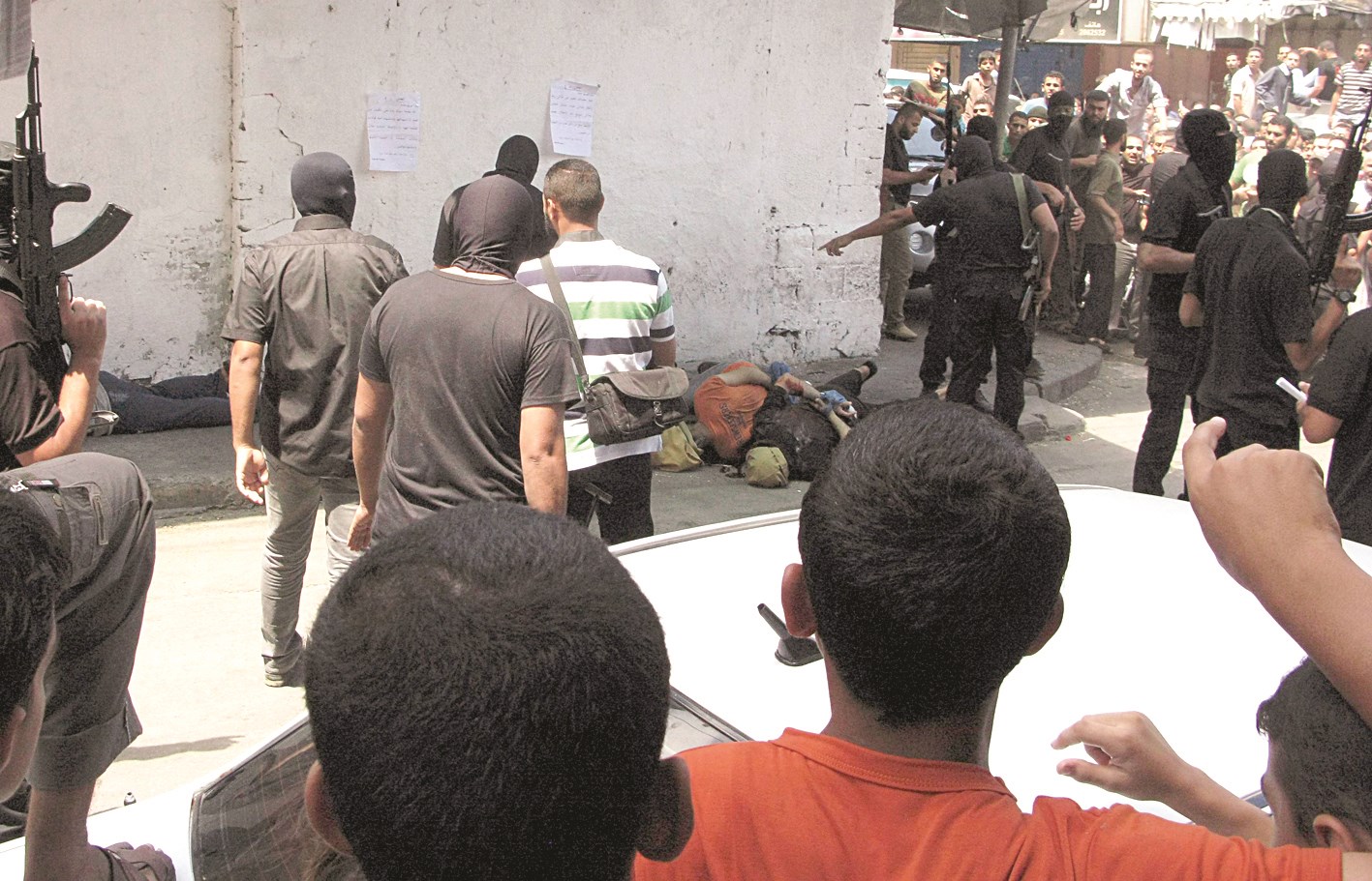 فلسطينيون متجمعون قرب جثث لأشخاص اتهموا بالعمالة لإسرائيل أعدمهم ملثمون من «حماس» في غزة أمس (رويترز)