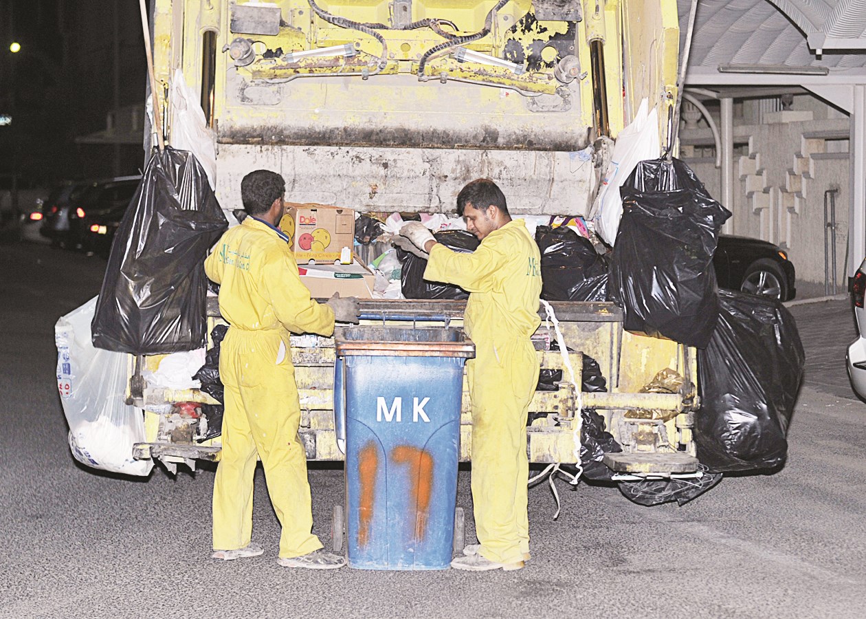 عمال يفرزون القمامة قبل نقلها للآلية
