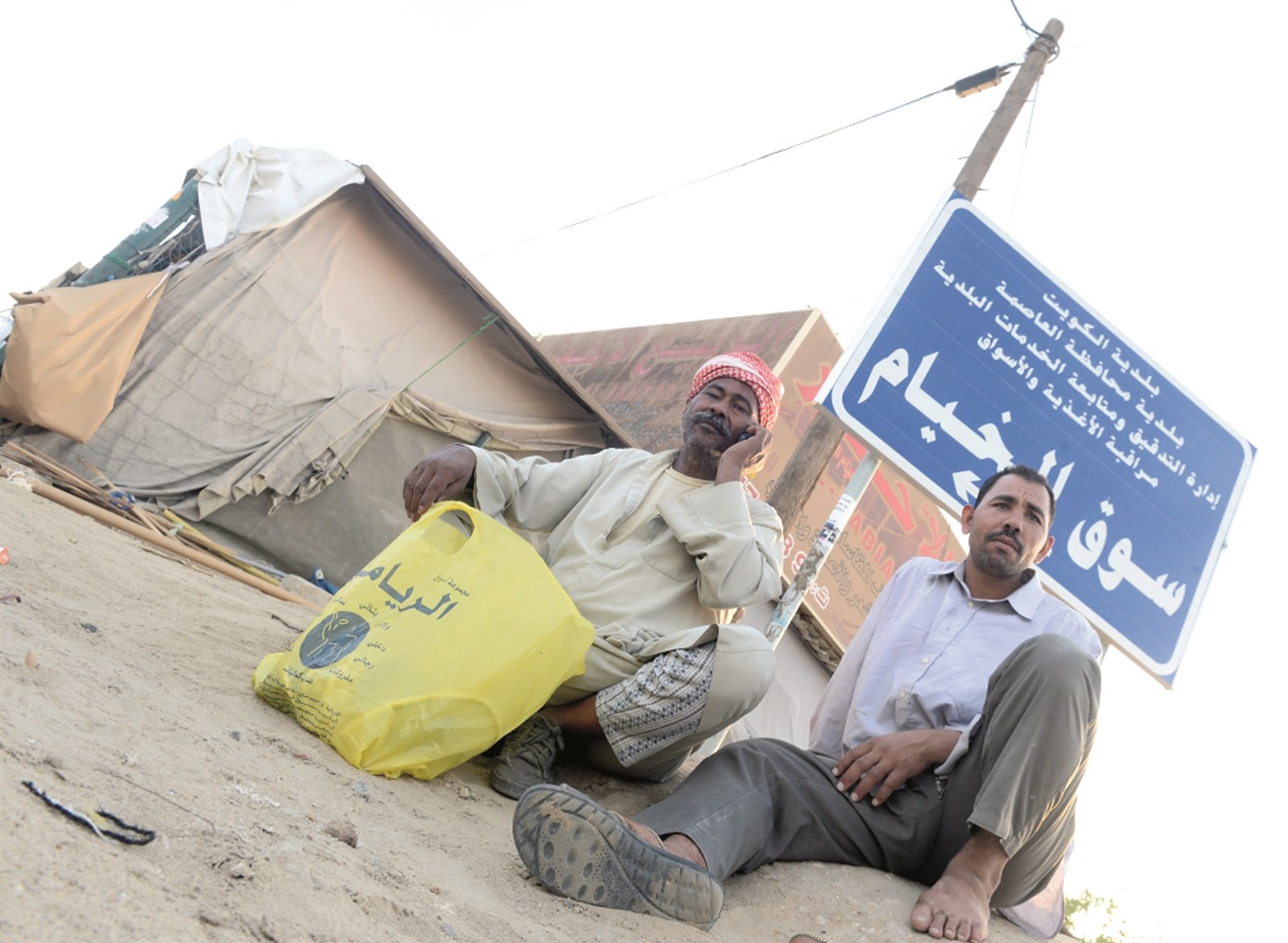 عاملان ينتظران زبوناً أمام السوق