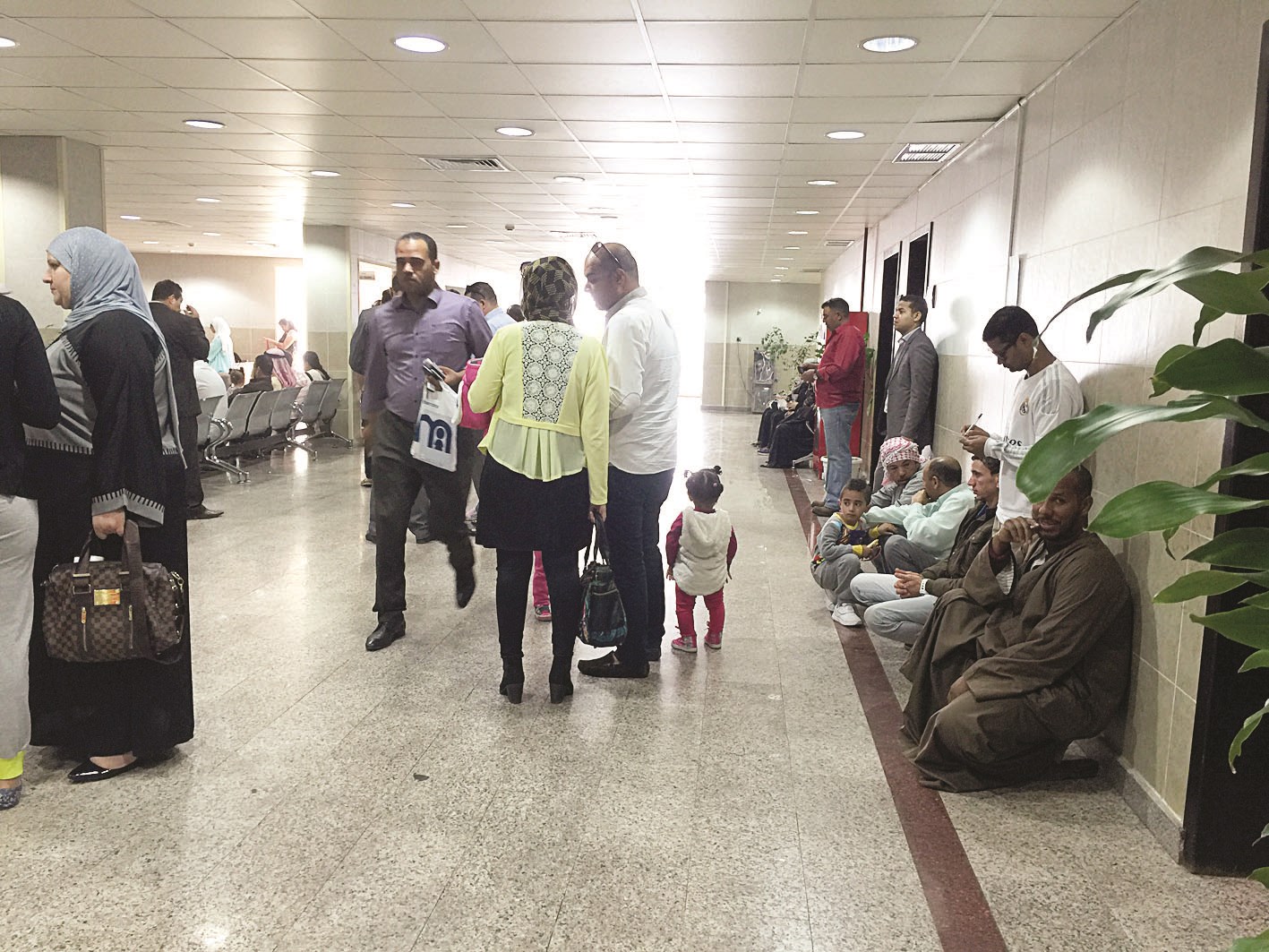 مراجعون افترشوا الأرض لطول فترة الانتظار