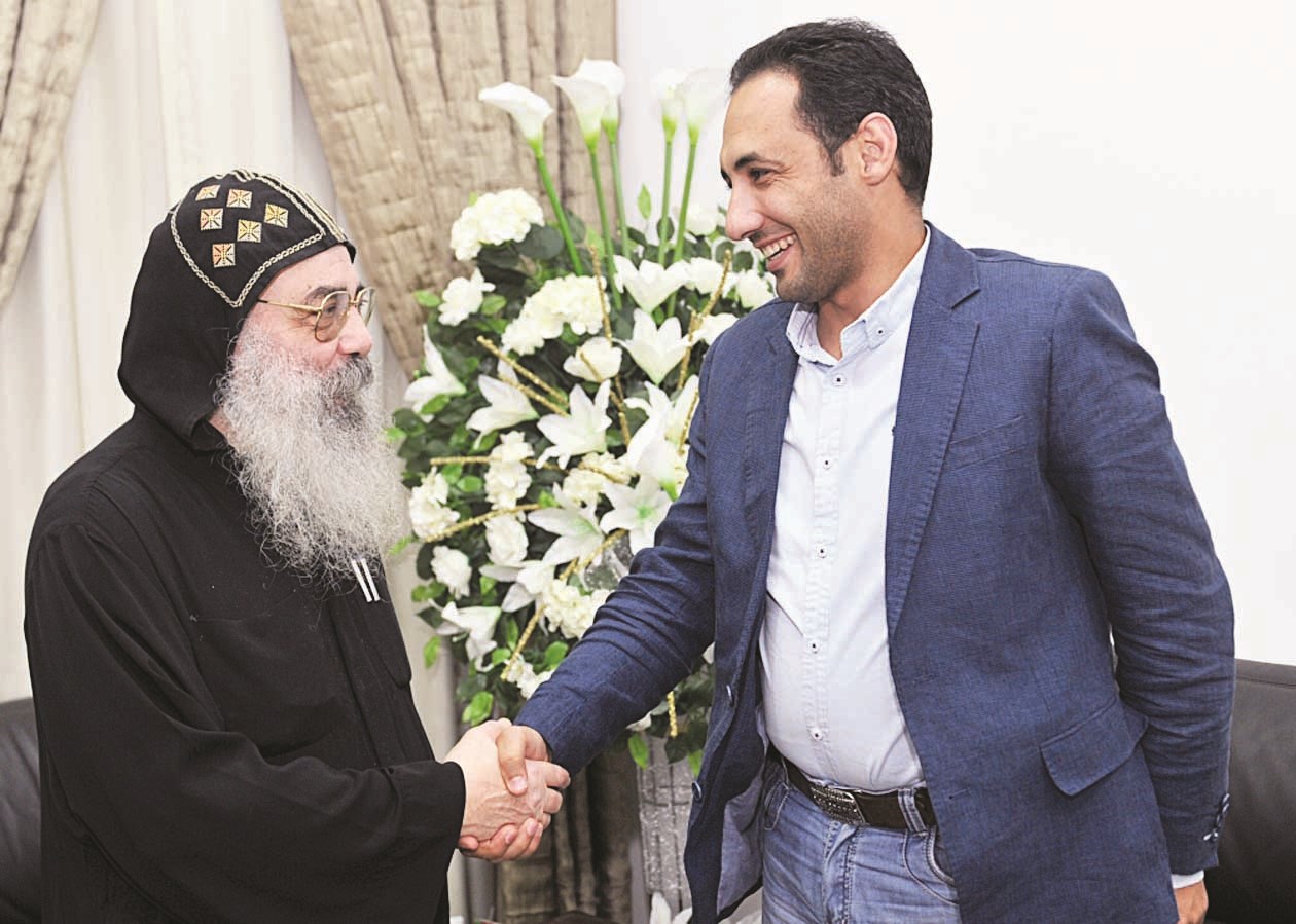 القمص بيجول مصافحاً الزميل أحمد زكريا (تصوير سعد هنداوي)