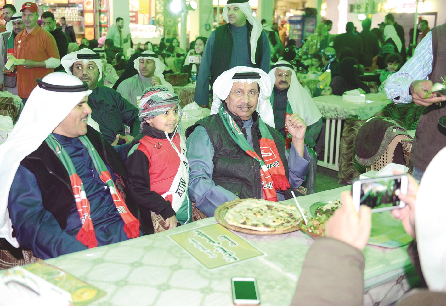 المبارك ملبّياً طلب أحد الأطفال للتصوير معه وإلى جانبه الوزير الحمود