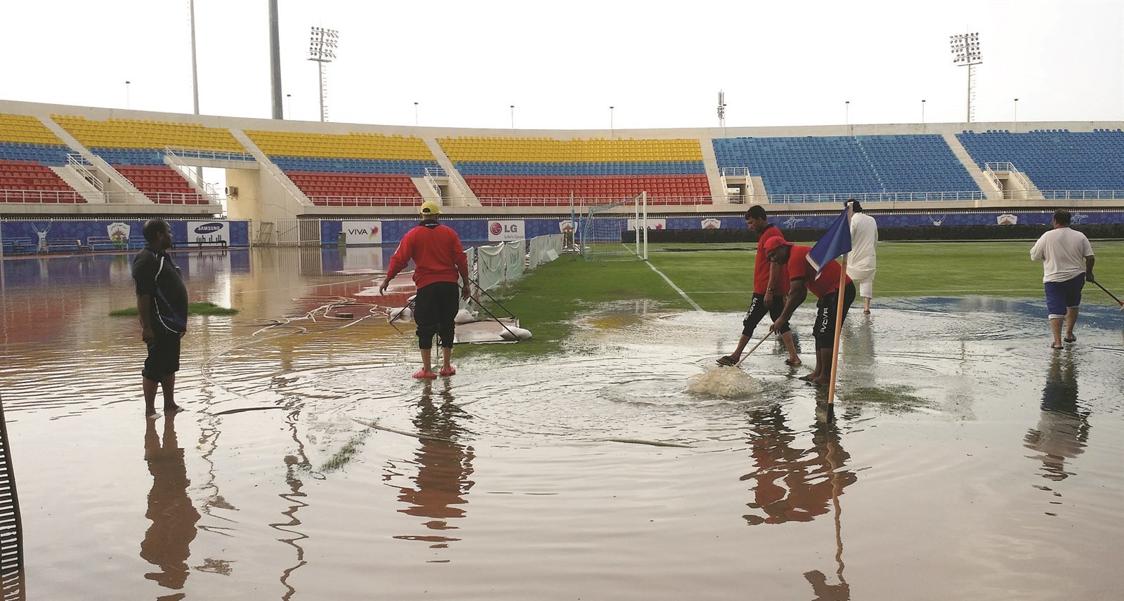 العمال يمسحون الماء من أرضية الملعب  (تصوير غانم السليماني)