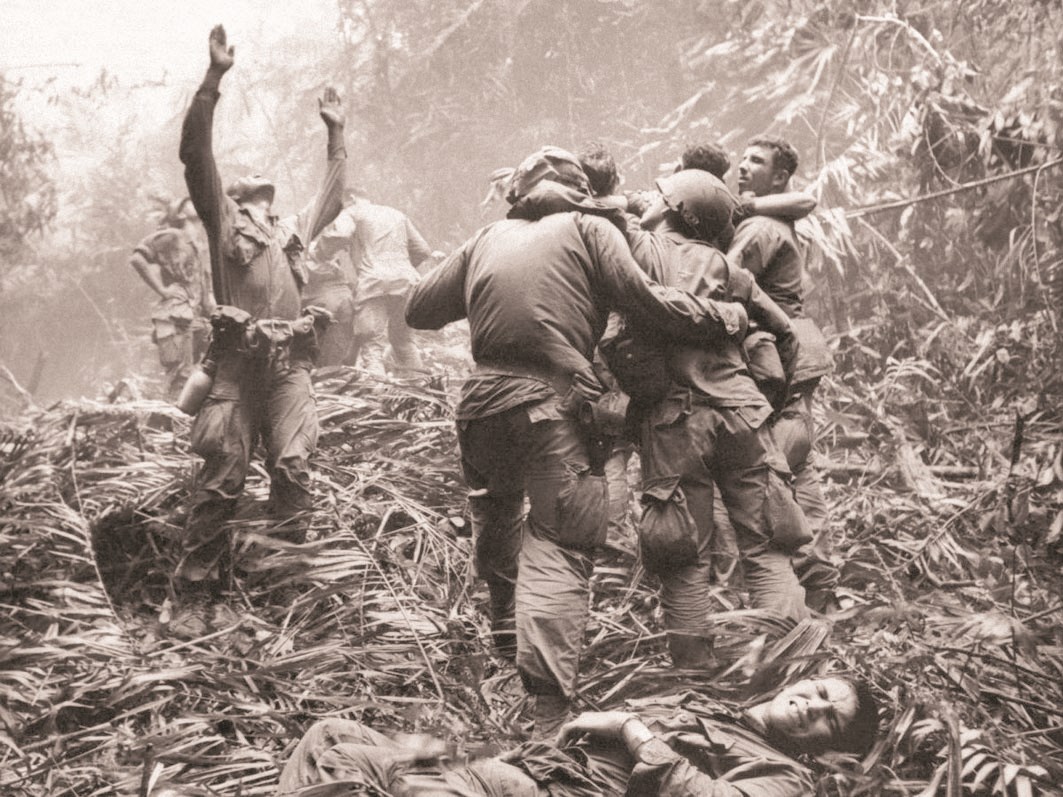 جنود أميركيون مصابون في أدغال فيتنام بينما يشير قائدهم إلى الأعلى مستغيثا بمروحية إسعاف عسكرية