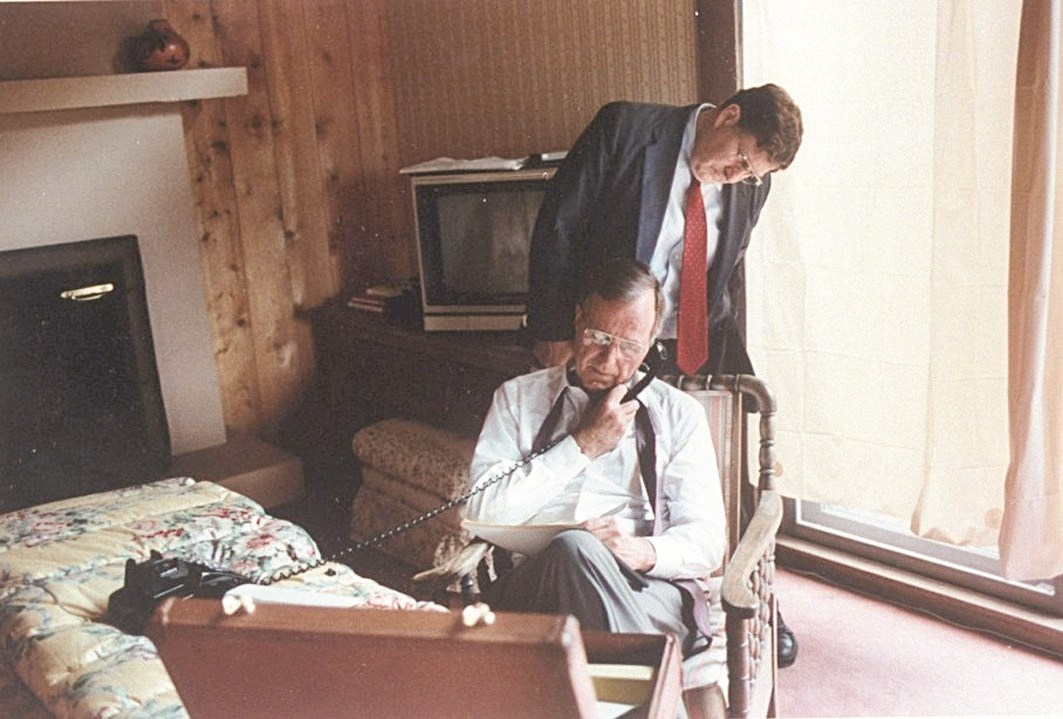 بوش الأب متحدثاً عبر الهاتف في البيت الأبيض ويبدو جون سنونو خلفه خلال متابعتهما لأخبار غزو الكويت في العام 1990