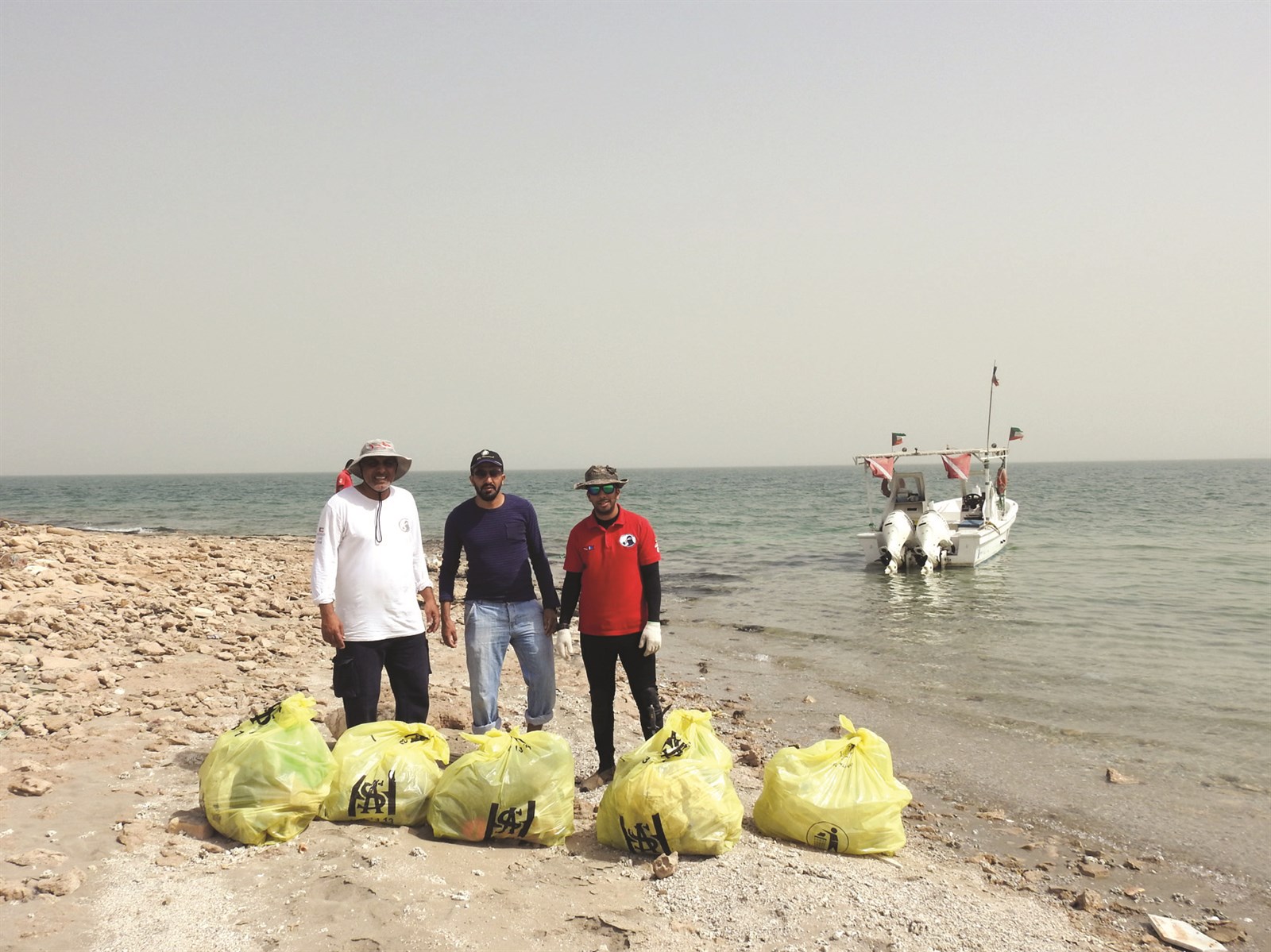 الزميل غانم السليماني متوسطاً عضوي فريق الغوص أمام أكياس المخلفات