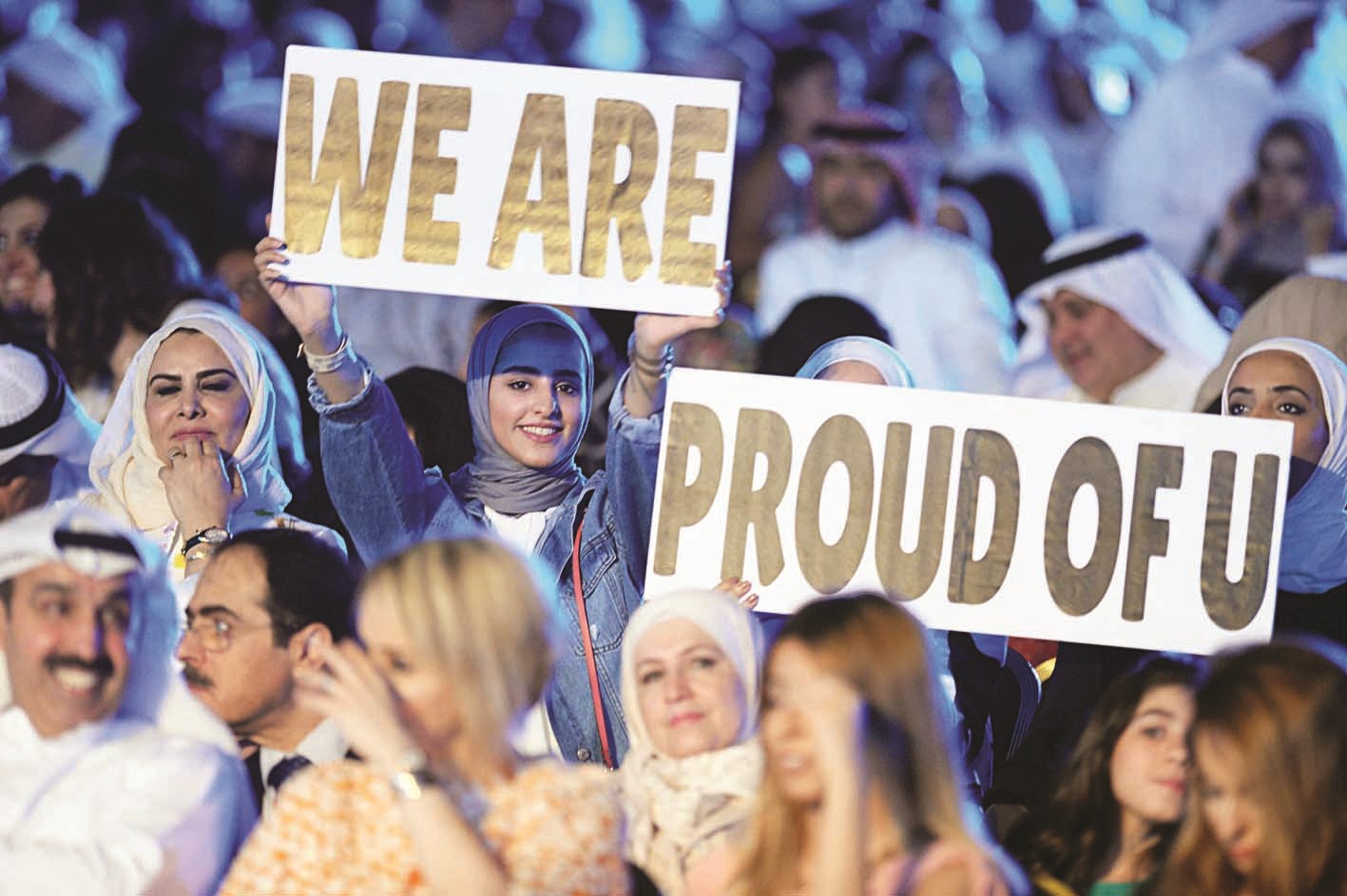 ذوو الخريجين يحملون لافتة «فخورون بك» بالإنكليزية احتفاءً بهم