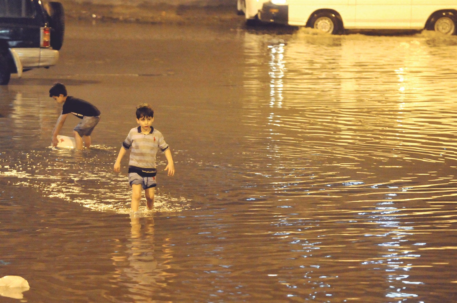 أطفال يلهون بالماء الذي غمر الشوارع