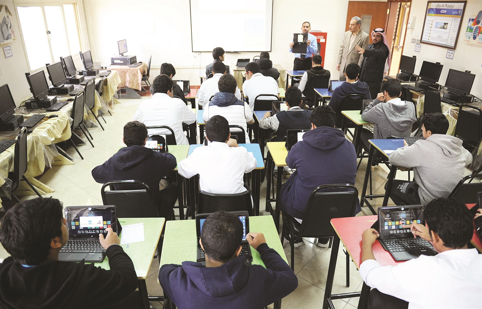 معلم يشرح للطلبة كيفية العمل على الجهاز