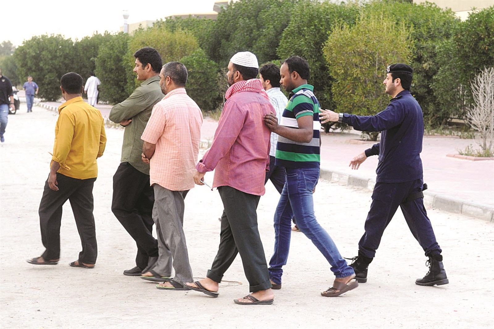 رجل أمن يقود عدداً من المضبوطين إلى الباص