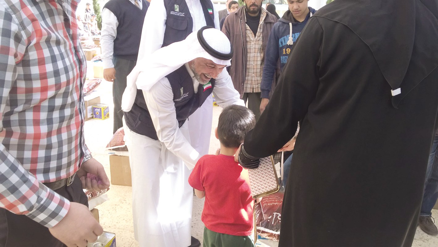 عضو في اللجنة يداعب طفلا من أبناء اللاجئين