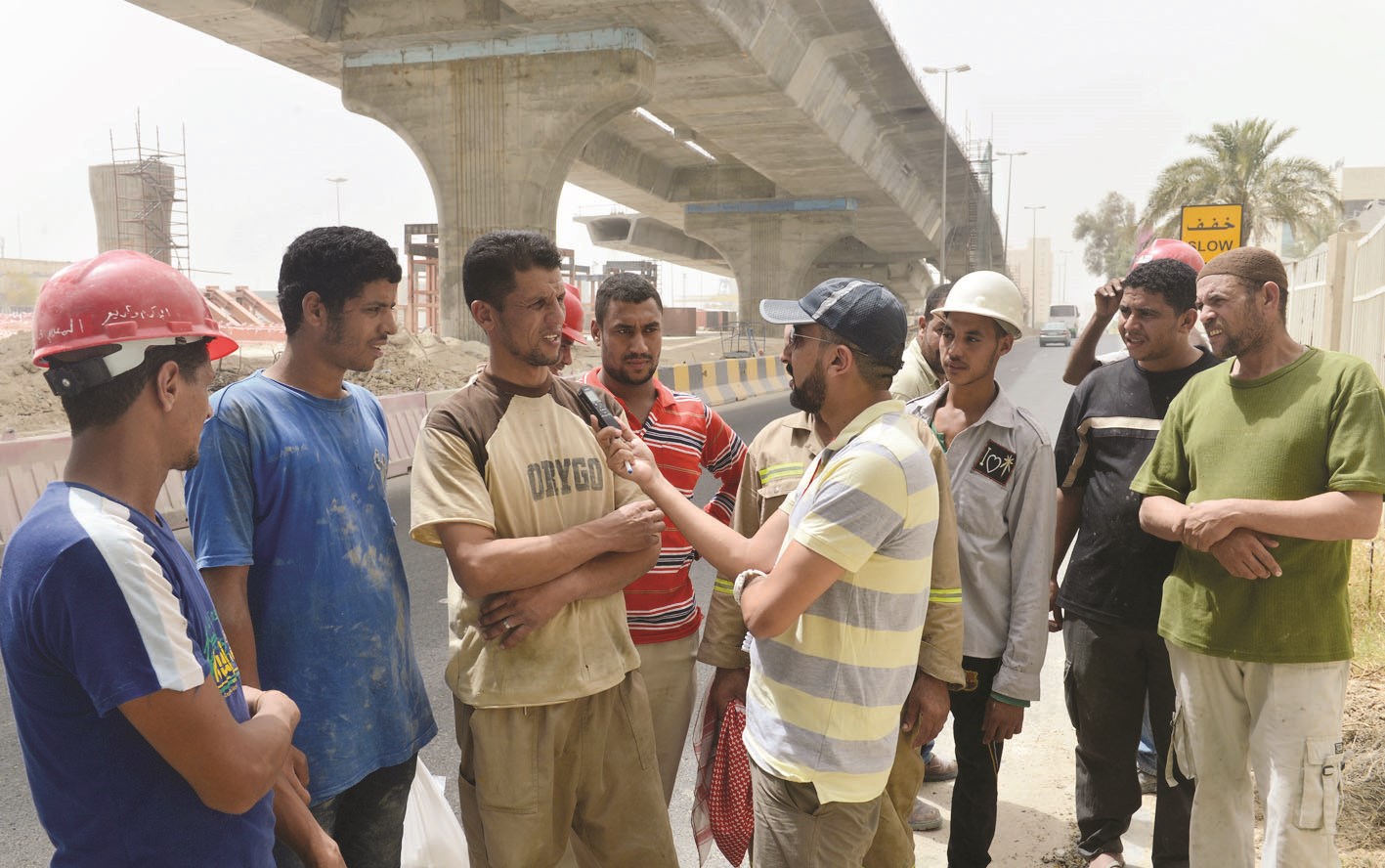 مجموعة من العمال يتحدثون إلى الزميل غانم السليماني