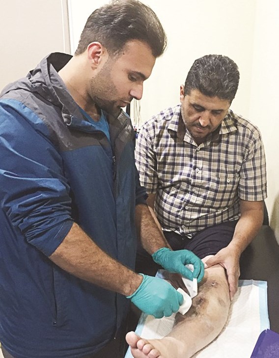 أحد أعضاء فريق الجمعية الطبية يعالج جريحاً في لبنان