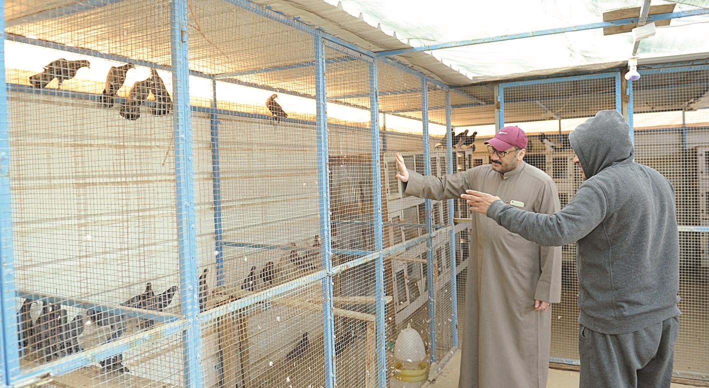 أحد المربين مع الزميل ناصر الفرحان أمام شبك طيوره