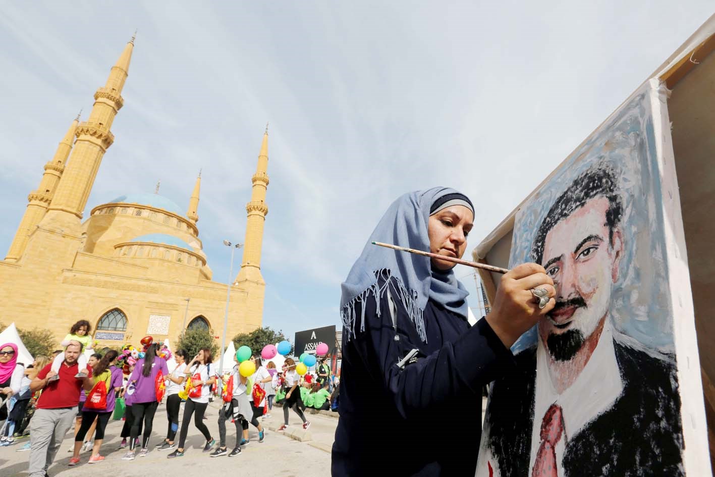 لبنانية ترسم لوحة للحريري على مقربة من مسجد محمد الأمين وسط العاصمة اللبنانية خلال أنشطة على هامش ماراثون بيروت الدولي أمس (رويترز)