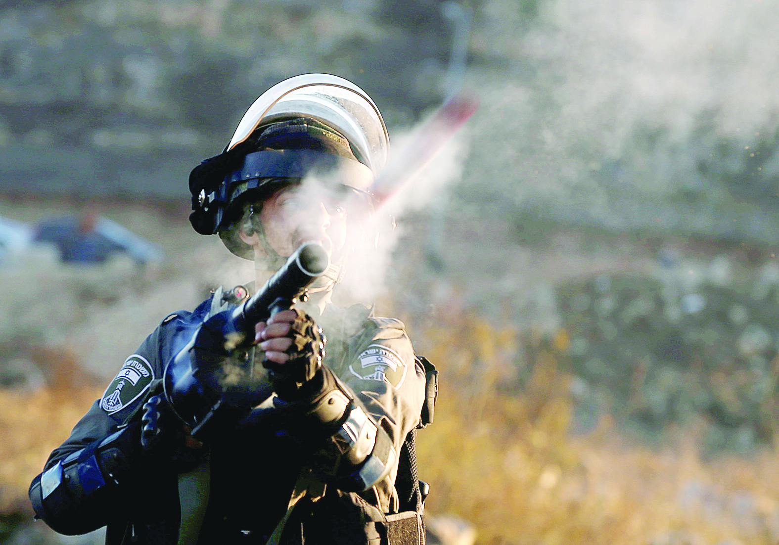 شرطي إسرائيلي يطلق قذيفة مسيلة للدموع لتفريق محتجين في الضفة 	(رويترز)