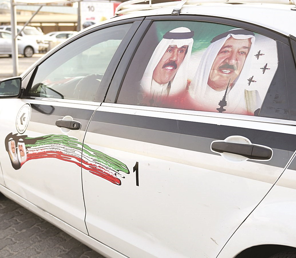 التاكسي مزيناً بصورتي سمو الأمير وولي العهد (تصوير جاسم البارون)