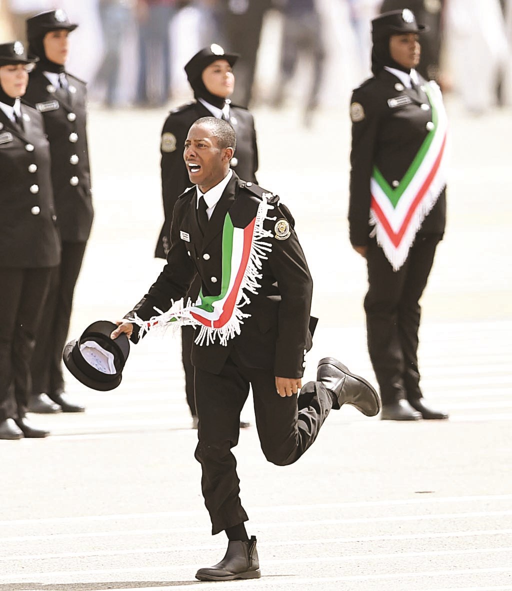 خرّيج يجري للاحتفال مع ذويه وفي الخلفية خرّيجات يقفن بثبات (تصوير جاسم بارون)