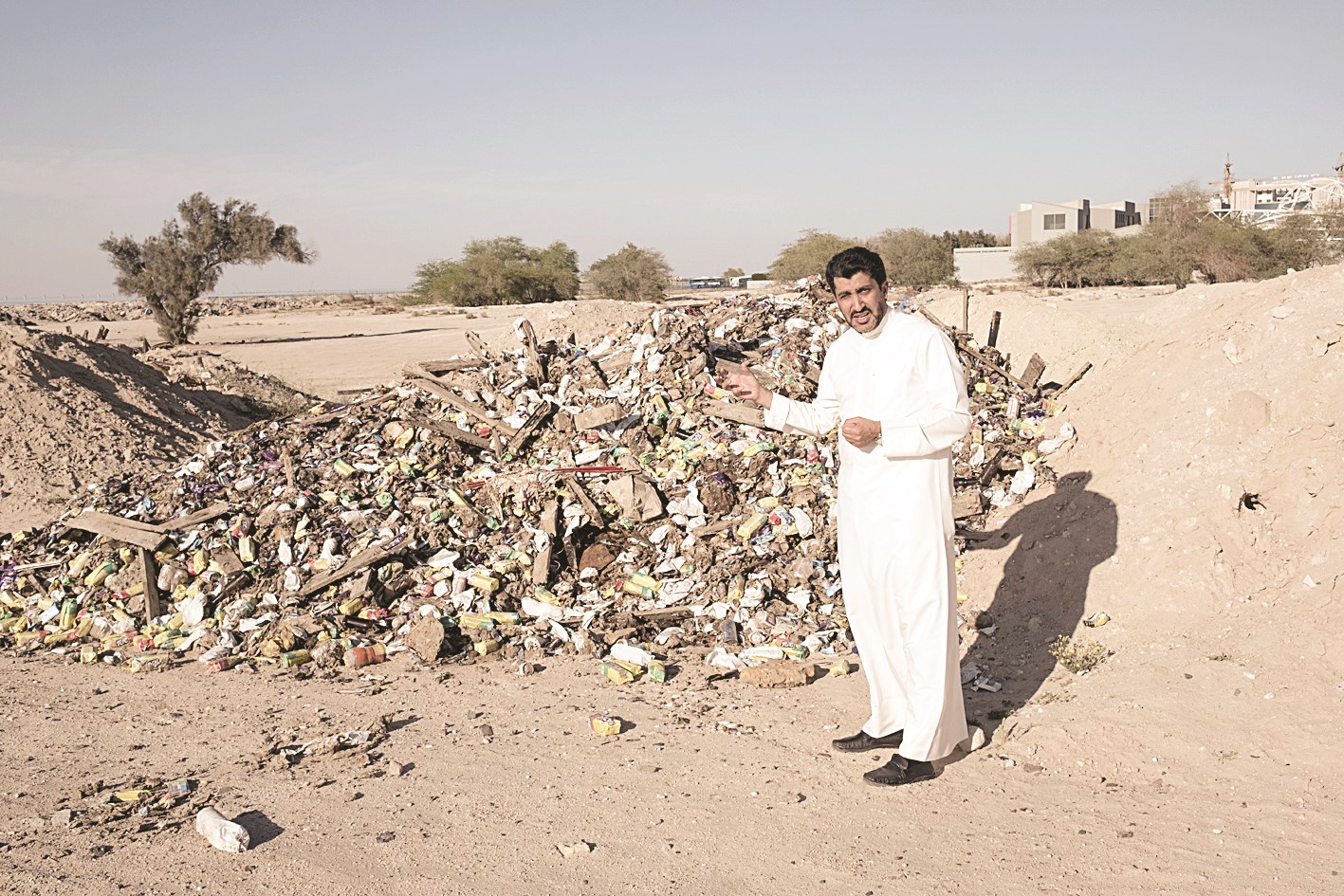 الزميل غانم السليماني يقف أمام كومة نفايات
