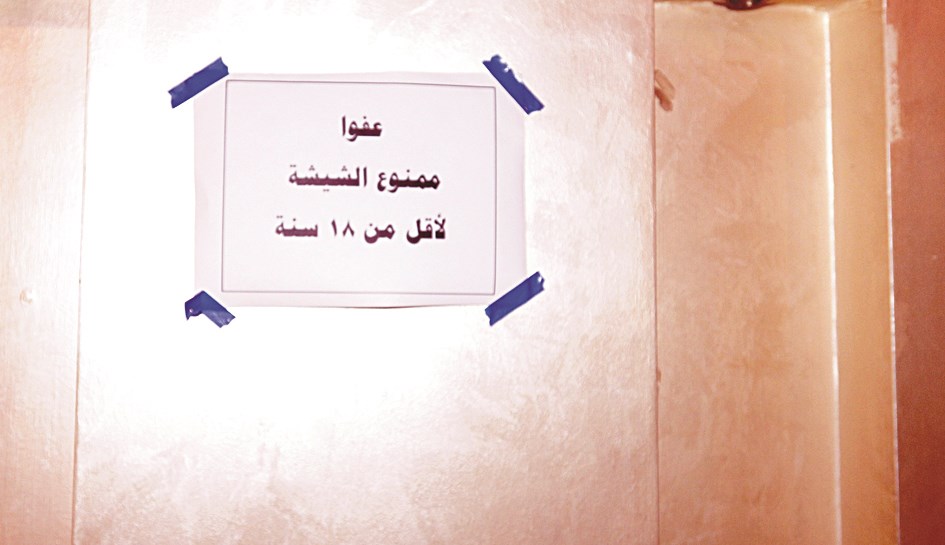 لوحة على جدار مقهى تمنع الشيشة لمن هم دون 18 عاما