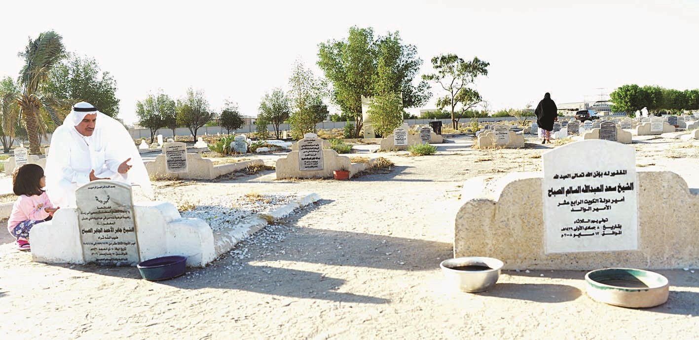 زائر مع صغيرته يقرأ الفاتحة أمام قبري المغفور لهما الشيخ جابر الأحمد والشيخ سعد العبدالله
