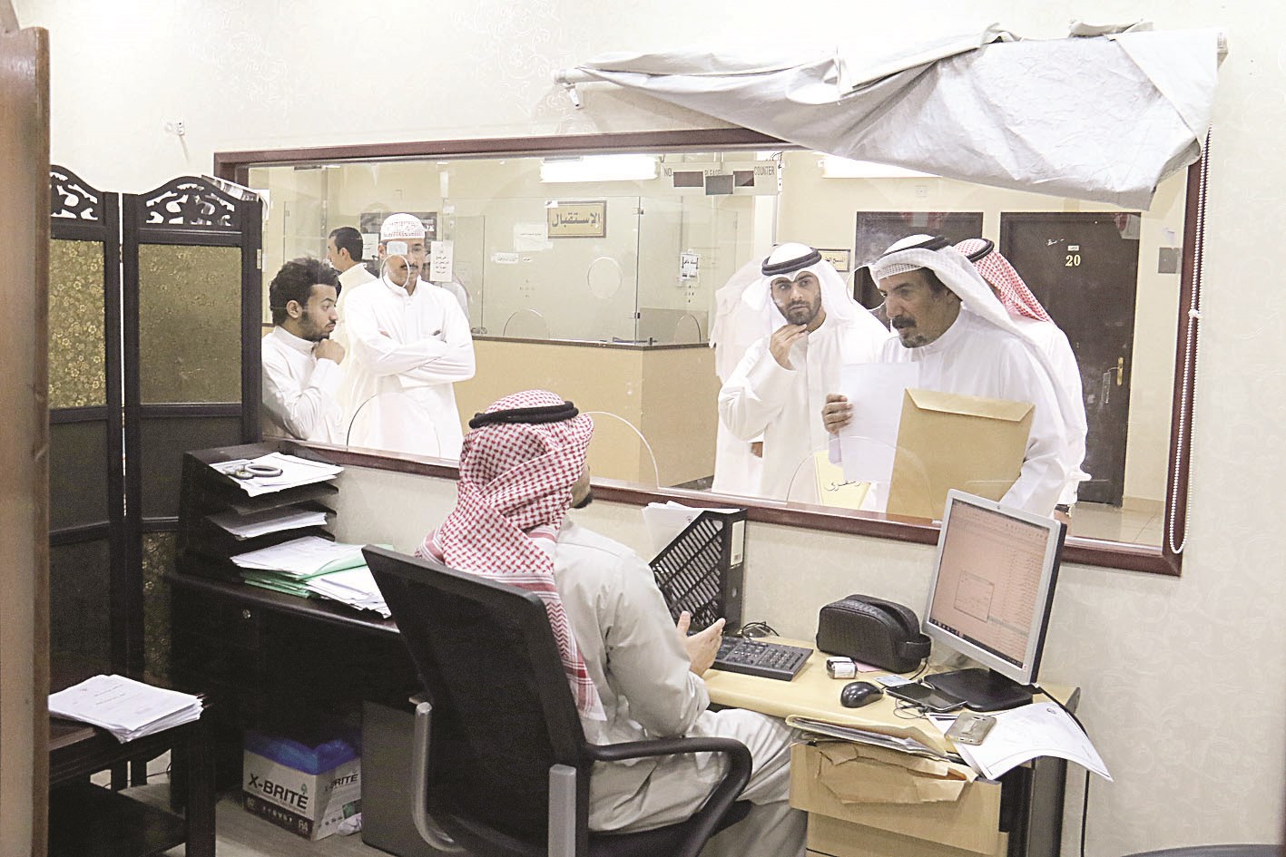 مراجعون يستفسرون من موظف في الإدارة عن الإجراءات