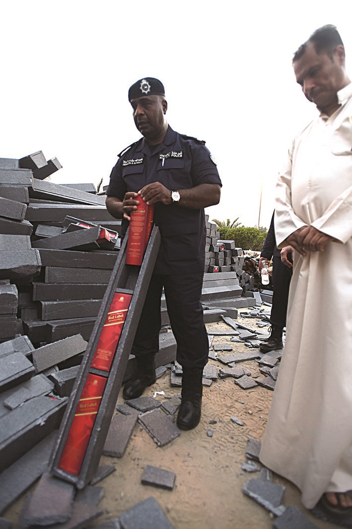 العميد سفاح مستخرجاً قناني خمر من مخبئها