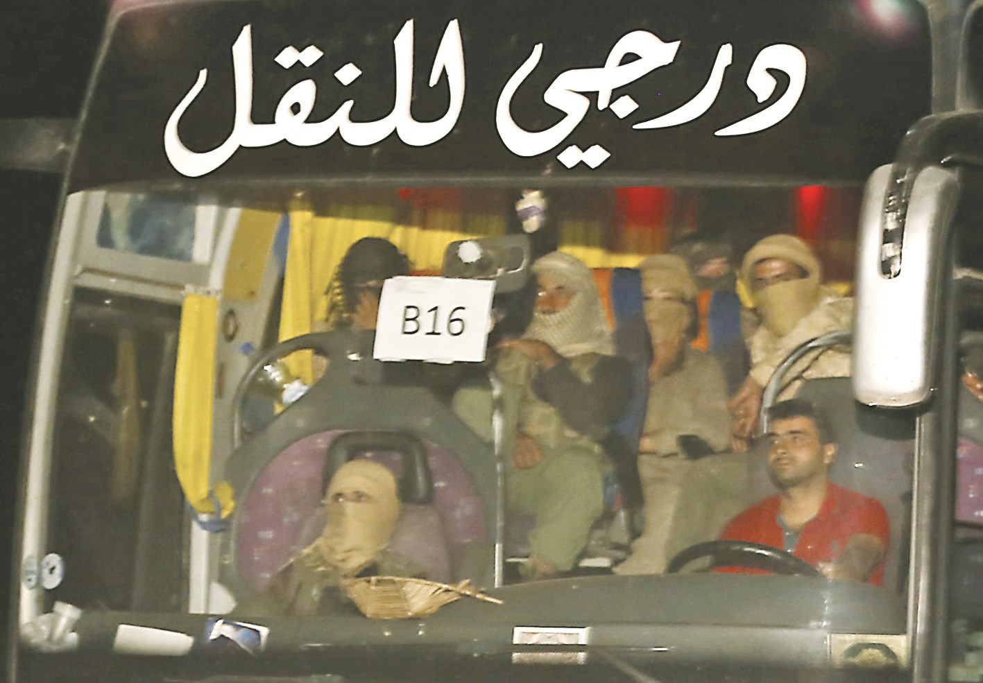 عناصر من «داعش» في أحد الباصات التي أقلتهم من الجرود على الحدود اللبنانية - السورية إلى دير الزور  (ا ف ب)