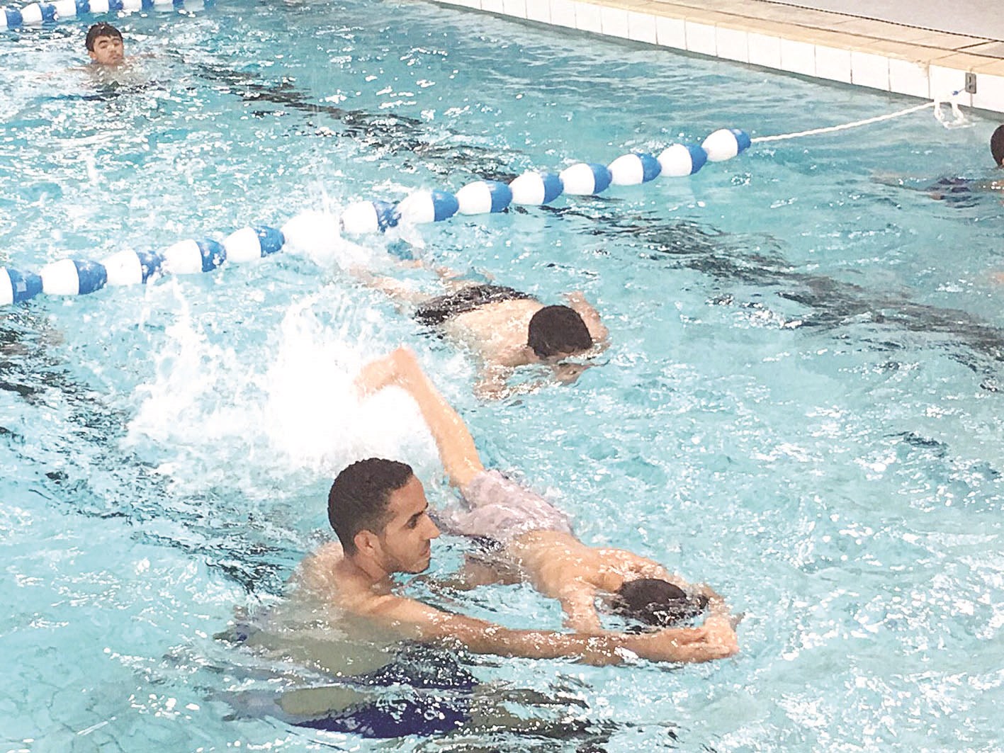 أحد المختصين يوجه متدرباً في حصة محو أمية السباحة