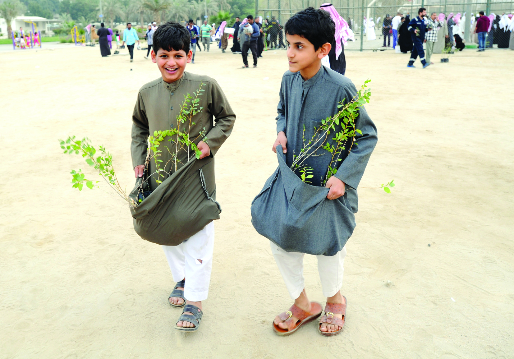 طفلان استعانا بثوبيهما لحمل الشتلات