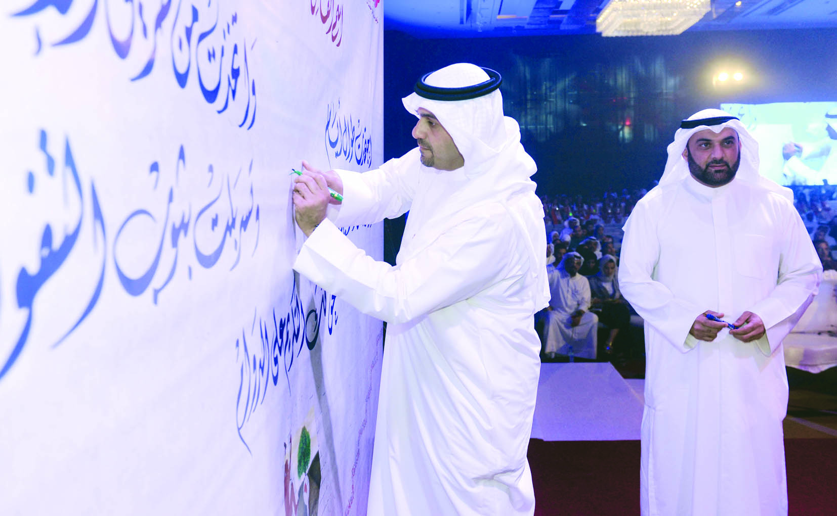 الوزير الصالح موقعاً على يافطة تحمل شعارات في الحفل