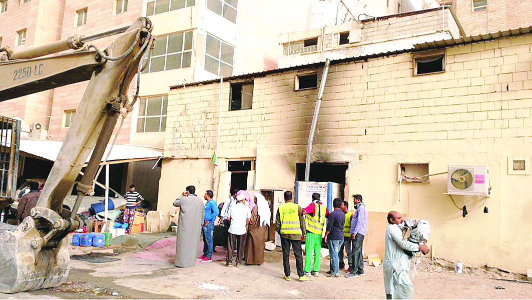 عمال يخلون منازلهم مع عمل الجرافة بإزالة المخالفات