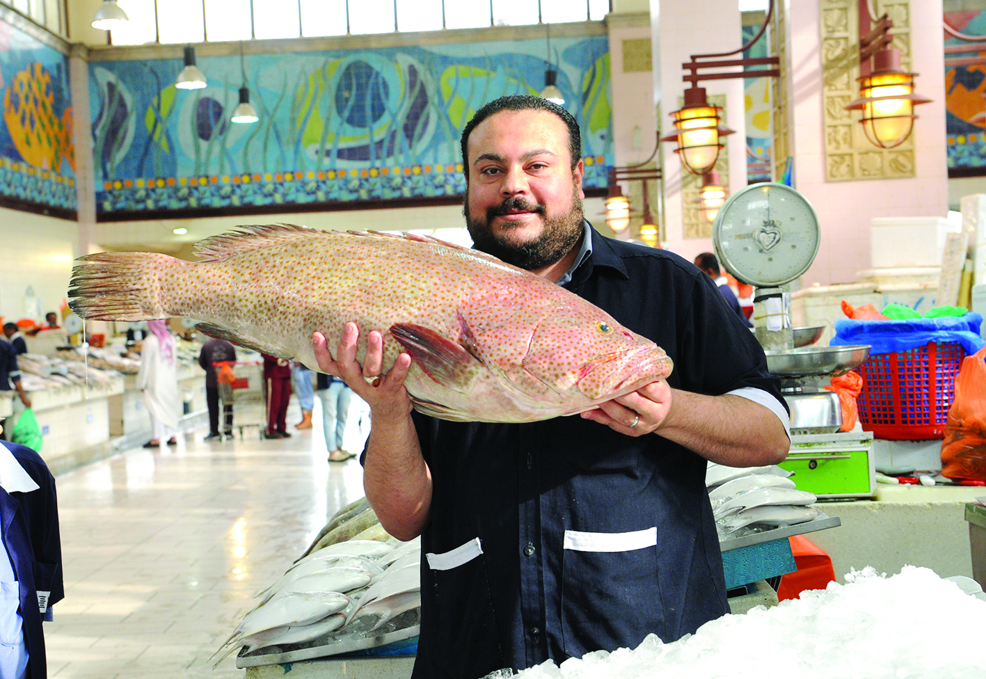 بائع يحمل سمكة هامور كبيرة