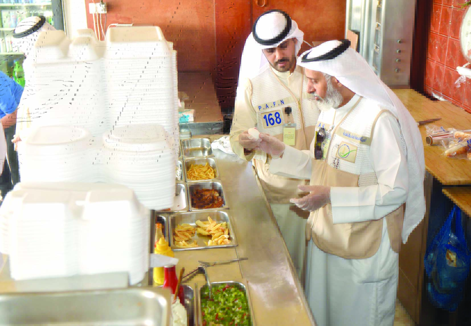 المفتشان العنزي والحربي يفحصان أغذية أحد المطاعم