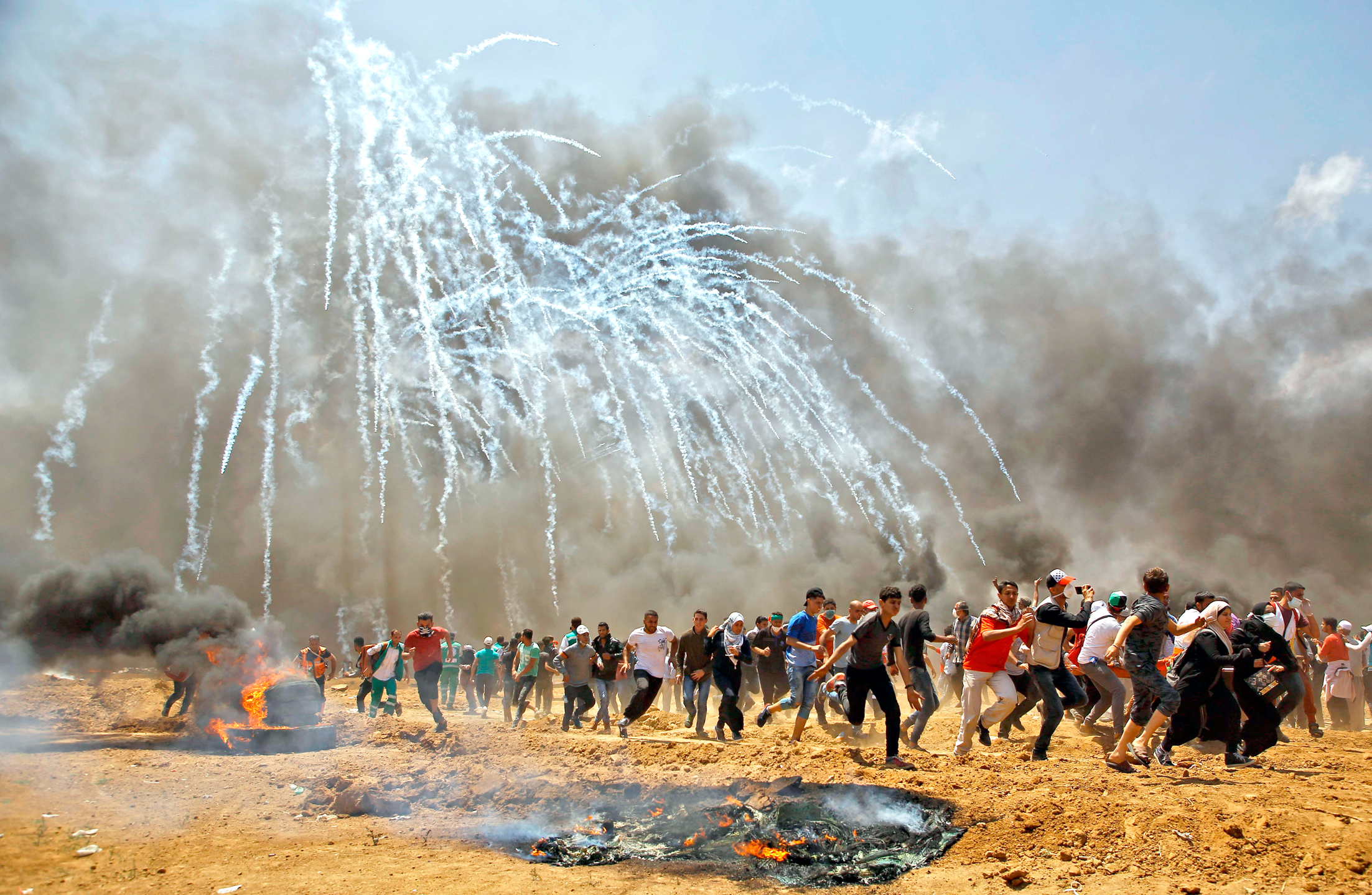فلسطينيون يهربون من قنابل الغاز المسيل للدموع على حدود غزة	 (ا ف ب)