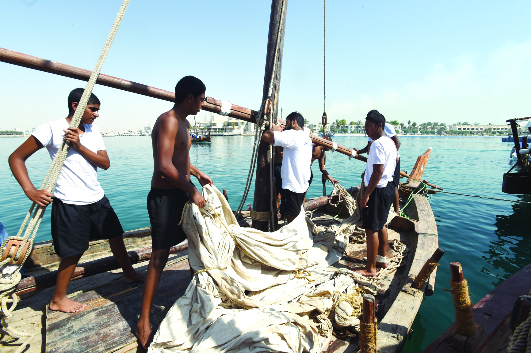 شباب الغوص في بداية يوم العمل يرفعون الأشرعة على المراكب 