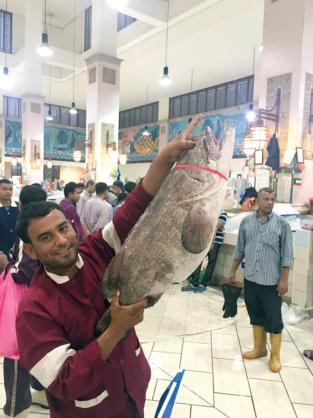 عامل يرفع سمكة هامور ضخمة