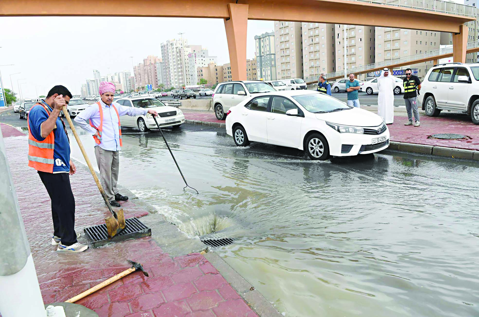 عمال يعملون على تسليك أحد مناهيل طريق الفحيحيل السريع لتصريف الأمطار